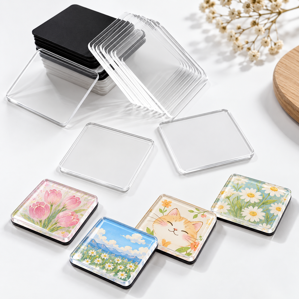 Clear acrylic squares and black magnetic pieces beside finished floral and landscape magnets.