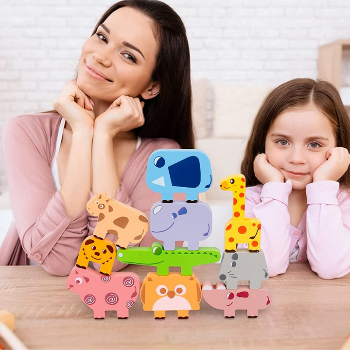 Adult and child seated behind a balanced arrangement of wooden animal blocks
