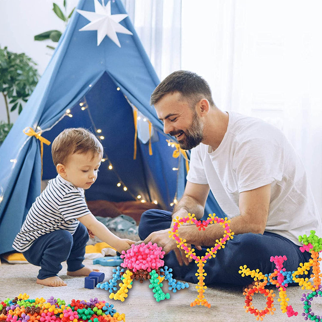Adult and child building colorful models together with snowflake-shaped blocks