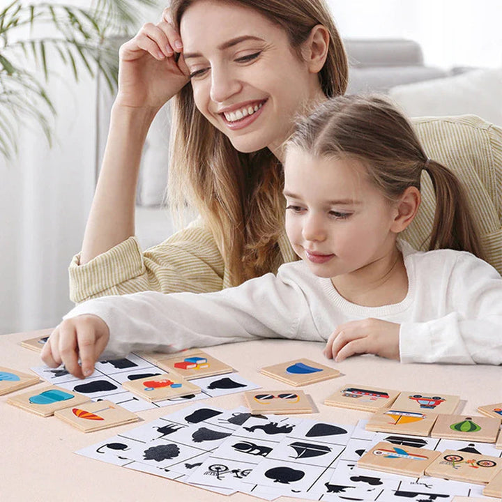 An adult and child matching wooden picture blocks to black silhouettes on play cards