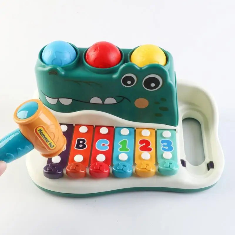 Front view of the green alligator xylophone with lettered and numbered keys and a hammer