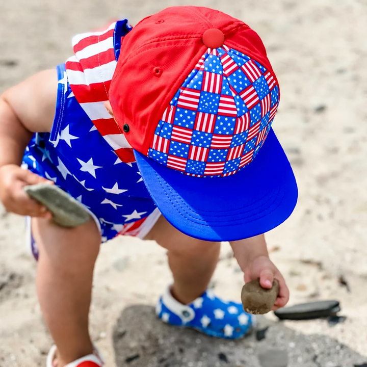 Overhead view of a child wearing a red and blue American flag-print cap at the beach