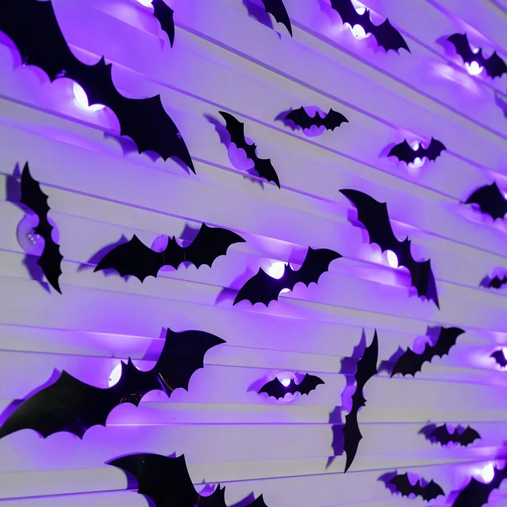 Angled view of black bat decorations casting purple light onto white wall panels