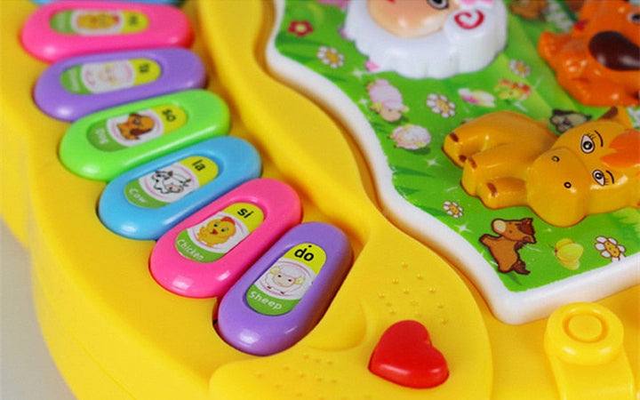 Close-up of colorful keys, animal buttons, and a red heart-shaped button on the yellow piano.