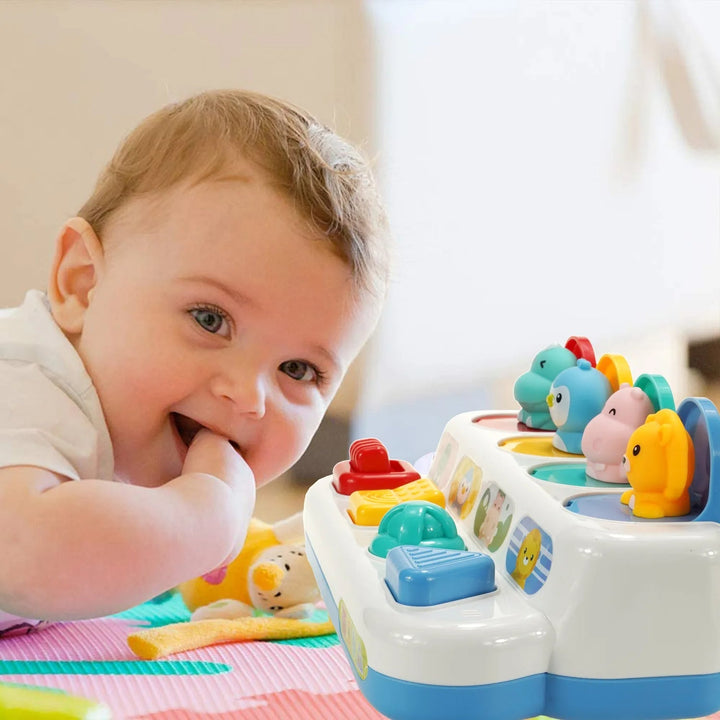 Baby lying beside the animal activity toy with four pop-up characters