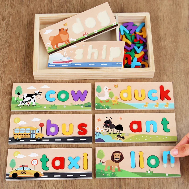 Letter-matching boards spelling cow, duck, bus, ant, taxi, and lion beside a wooden storage tray