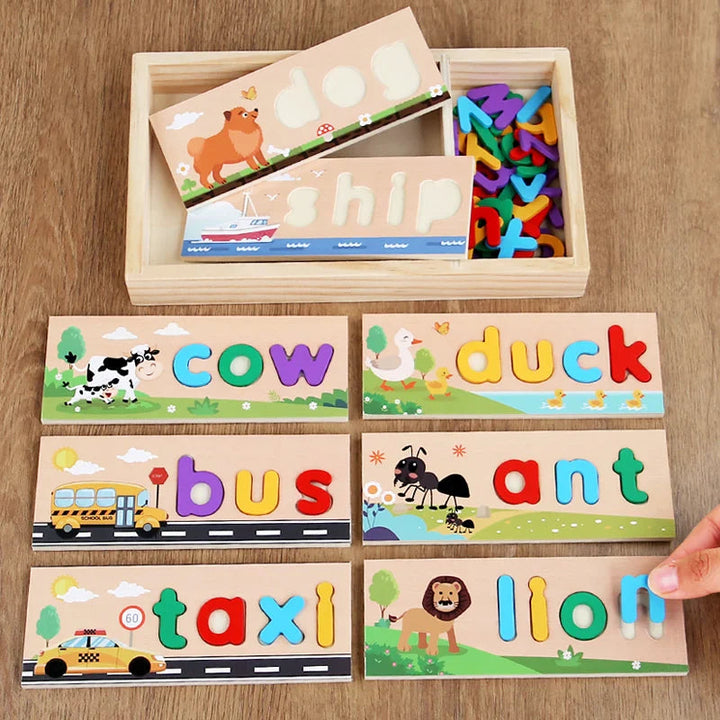 Letter-matching boards spelling cow, duck, bus, ant, taxi, and lion beside a wooden storage tray