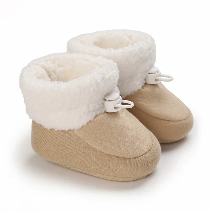 Apricot baby winter boots with rounded toes, fluffy white cuffs, and white toggles