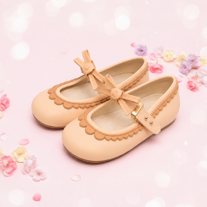 Apricot Mary Jane shoes with bow straps and scalloped trim on a pink floral background