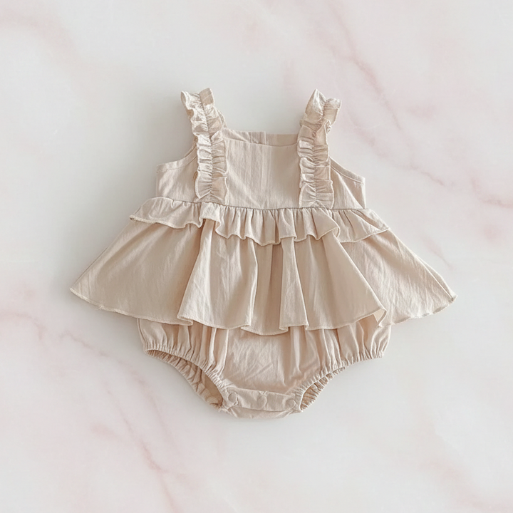 Apricot baby dress romper with ruffled straps, a skirt overlay and an integrated bloomer