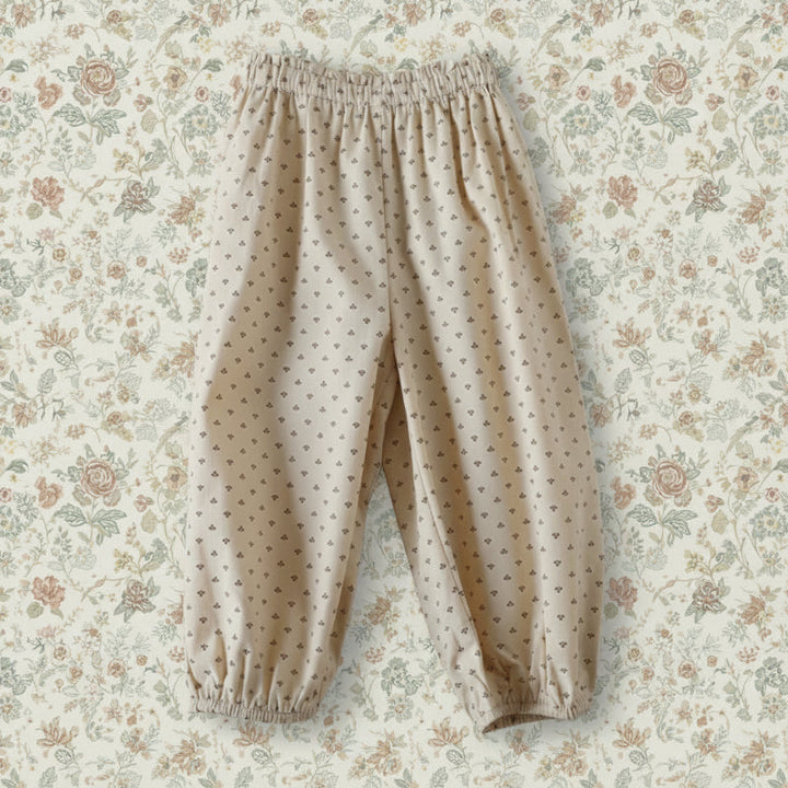 Apricot harem pants with a tiny all-over print and elastic cuffs, laid flat.