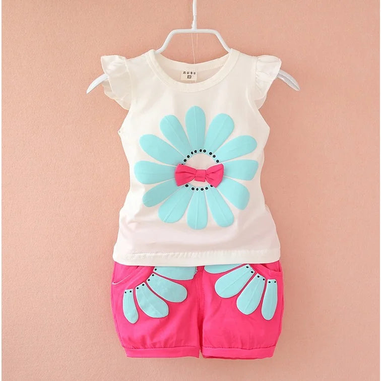 White ruffle-shoulder baby top with an aqua flower and bright pink floral shorts