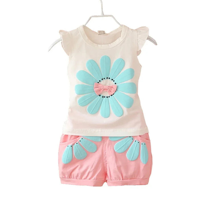 White top with an aqua flower and pale pink floral shorts against a white background
