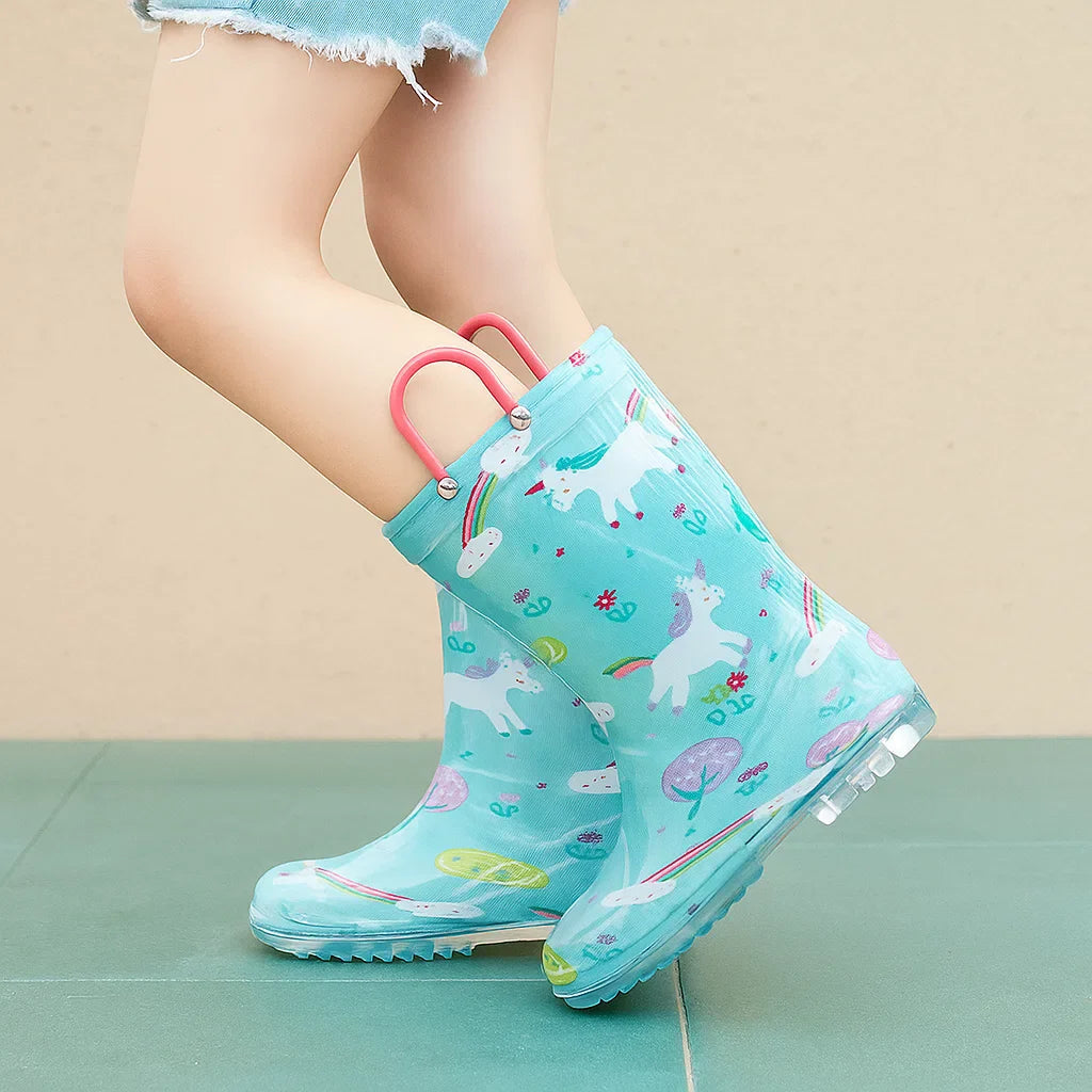 Child wearing aqua unicorn-print rain boots with pink loops and denim shorts