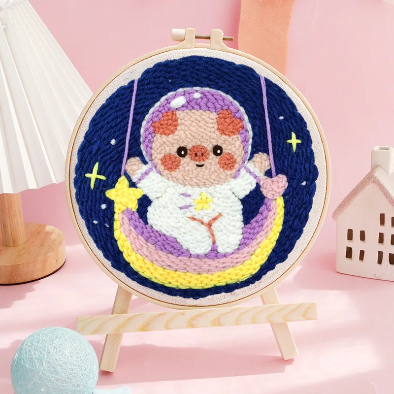 Astronaut punch needle hoop with a purple helmet, yellow crescent swing, and starry blue background