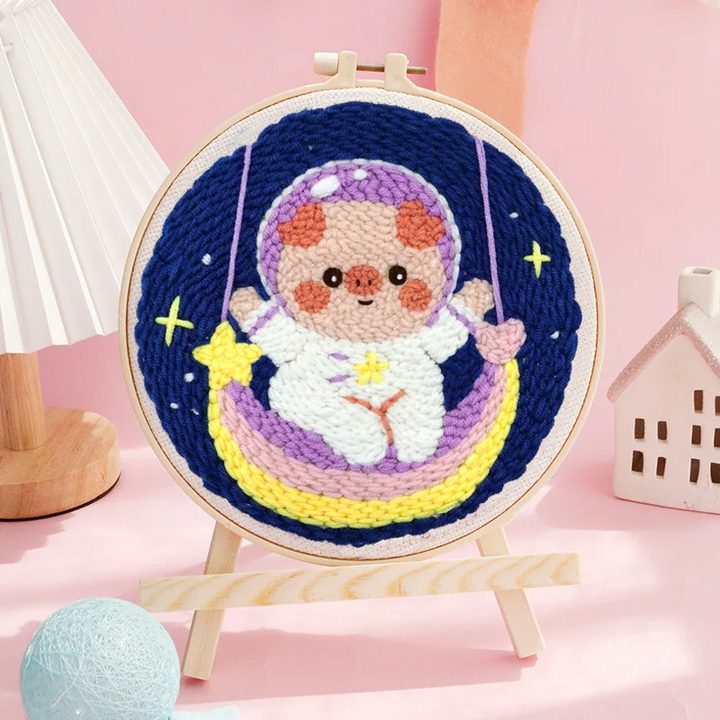 Astronaut punch needle hoop with a purple helmet, yellow crescent swing, and starry blue background
