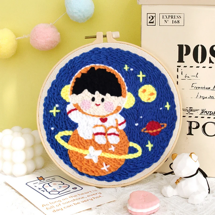 Astronaut punch needle hoop with an orange ringed planet against a blue background