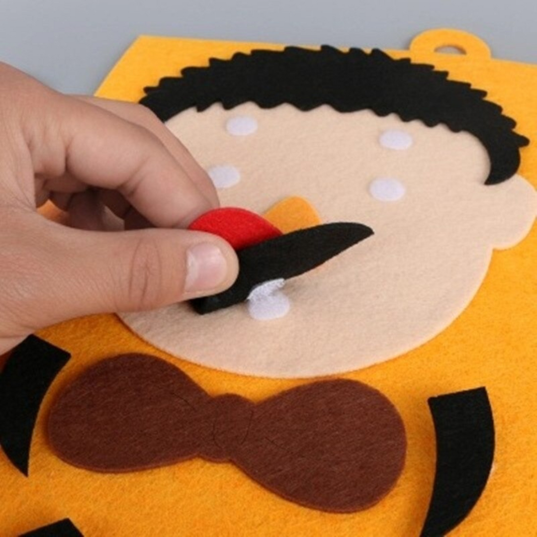 Close-up of a hand attaching a felt mouth to an orange character board