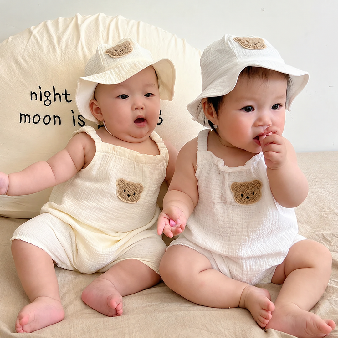 Two babies wearing bear-patch overalls and coordinating bucket hats