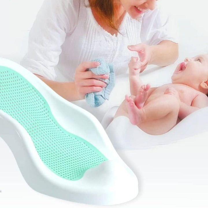 Caregiver washing a baby with a green mesh bath seat shown in the foreground