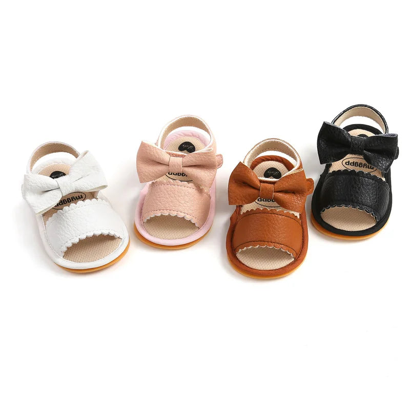 Baby bow sandals in off-white, pink, brown, and black arranged together