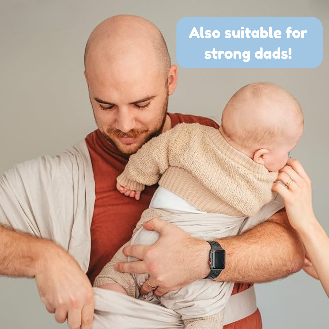 Dad holding a baby against his chest while adjusting the light-colored carrier&