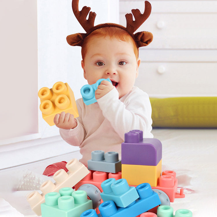 Baby holding yellow and blue silicone blocks beside a pile of colorful pieces