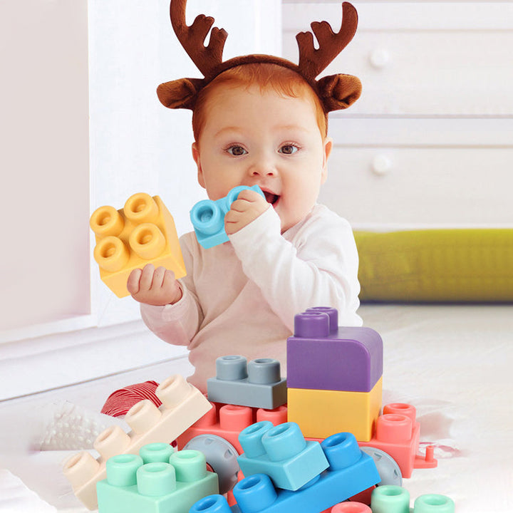Baby holding yellow and blue silicone blocks beside a pile of colorful pieces