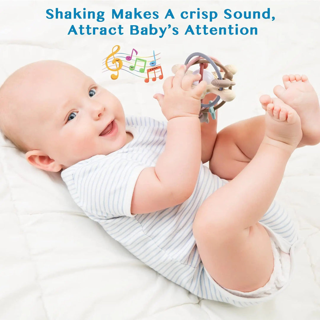 Baby lying on a blanket and grasping a looped silicone teething ball