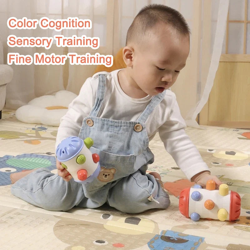 Baby holding a blue-ended sensory roller with a red-ended roller nearby on a play mat