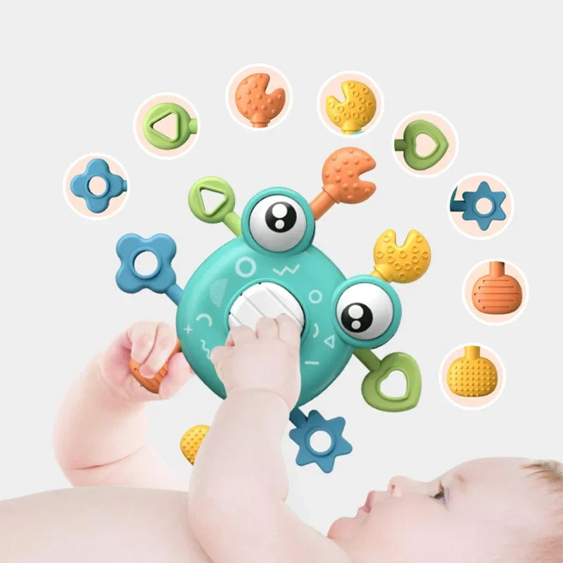 Baby holding a green crab sensory toy with a large white center button