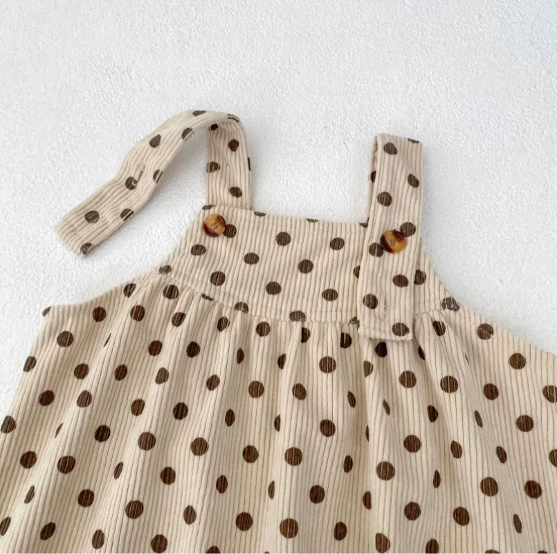 Apricot polka-dot jumpsuit with one shoulder strap unfastened to show the button closure.