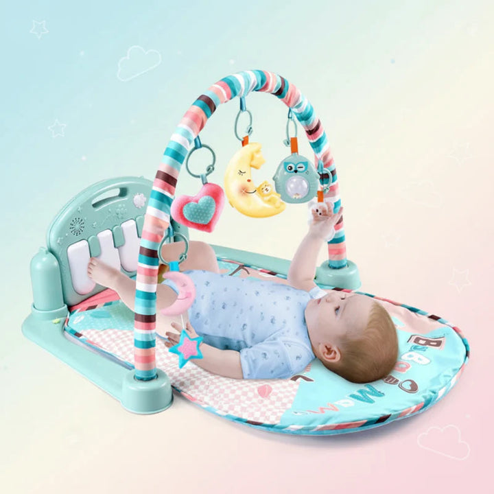 Baby lying on a mint play gym mat beneath a striped arch with hanging toys