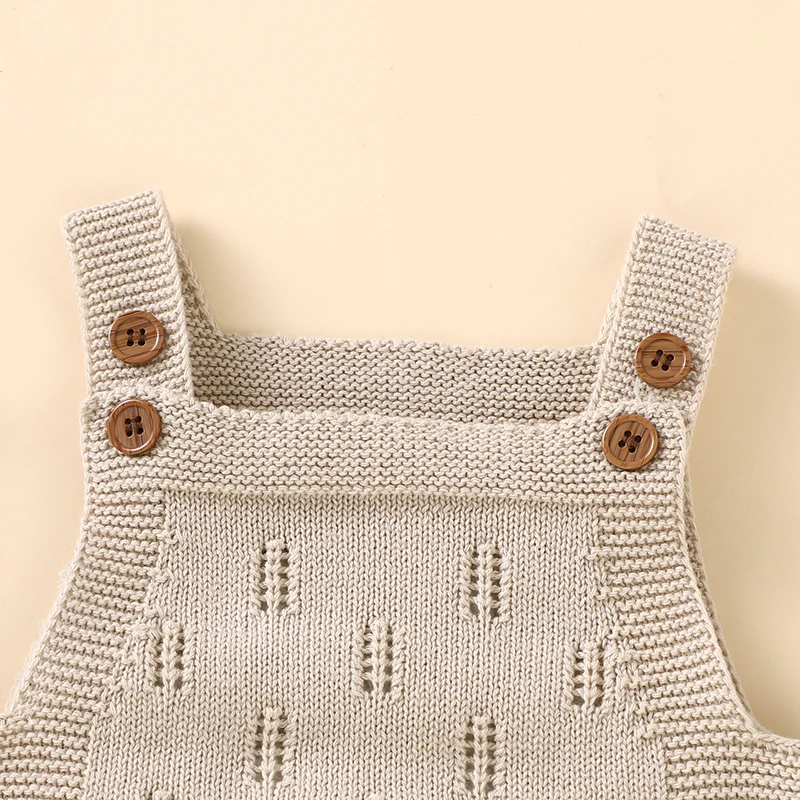 Close-up of the square neckline, textured knit, and two-button shoulder straps on beige baby overalls.