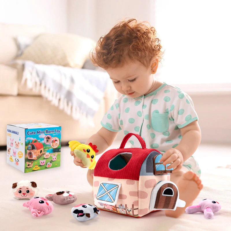 Baby playing with a soft red-roof farmhouse and plush farm animals