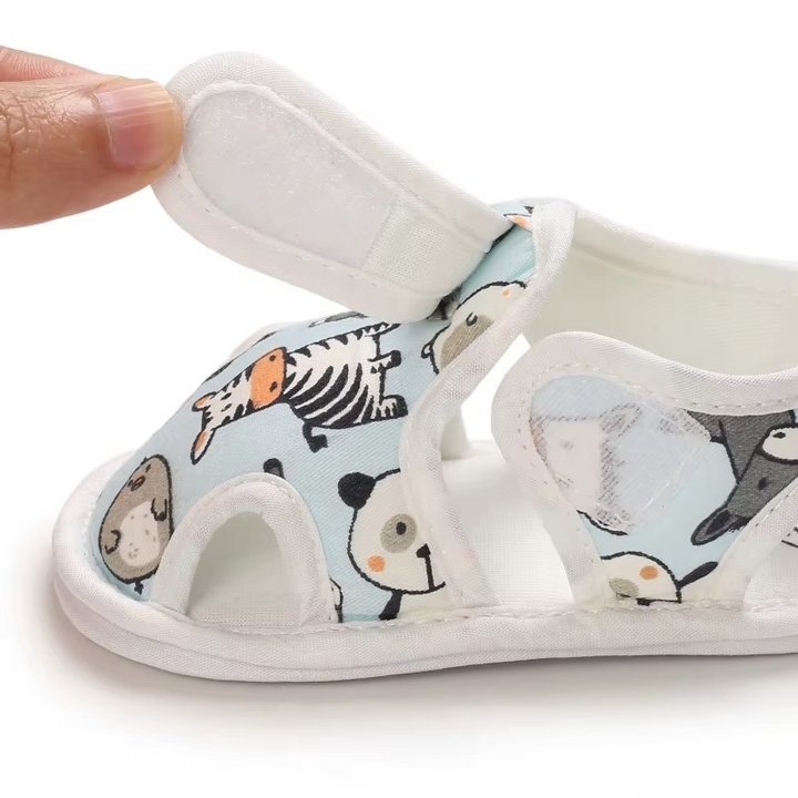 Open hook-and-loop ankle strap on a light blue animal-print baby sandal