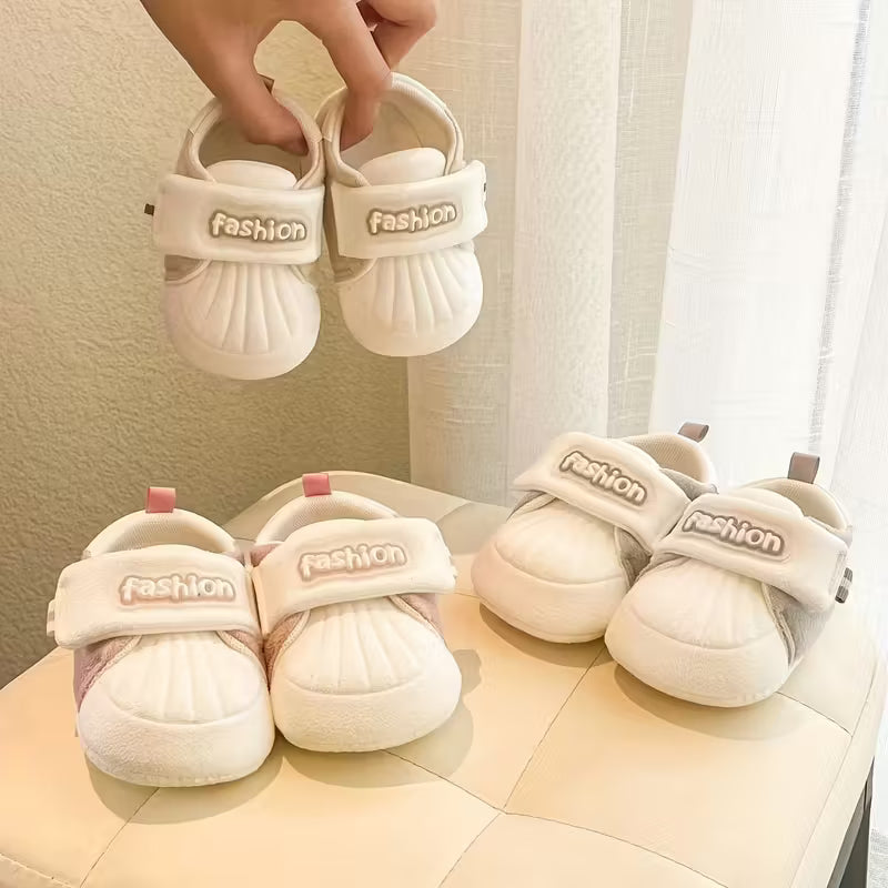 Baby sandals with adjustable straps arranged beside a window