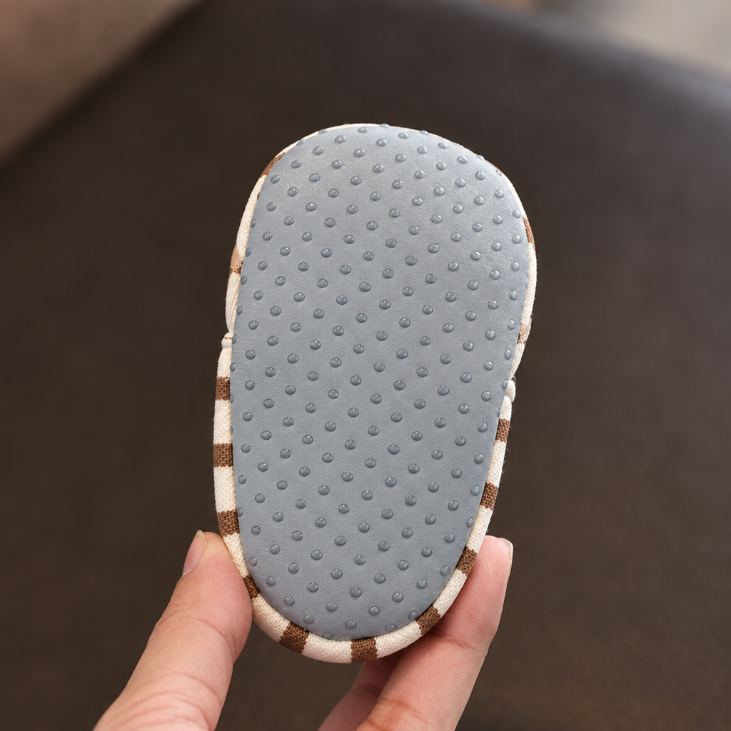 Gray sole of a striped baby shoe with small raised dots