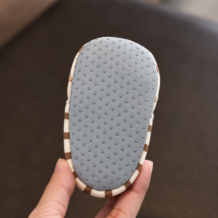 Gray sole of a striped baby shoe with small raised dots