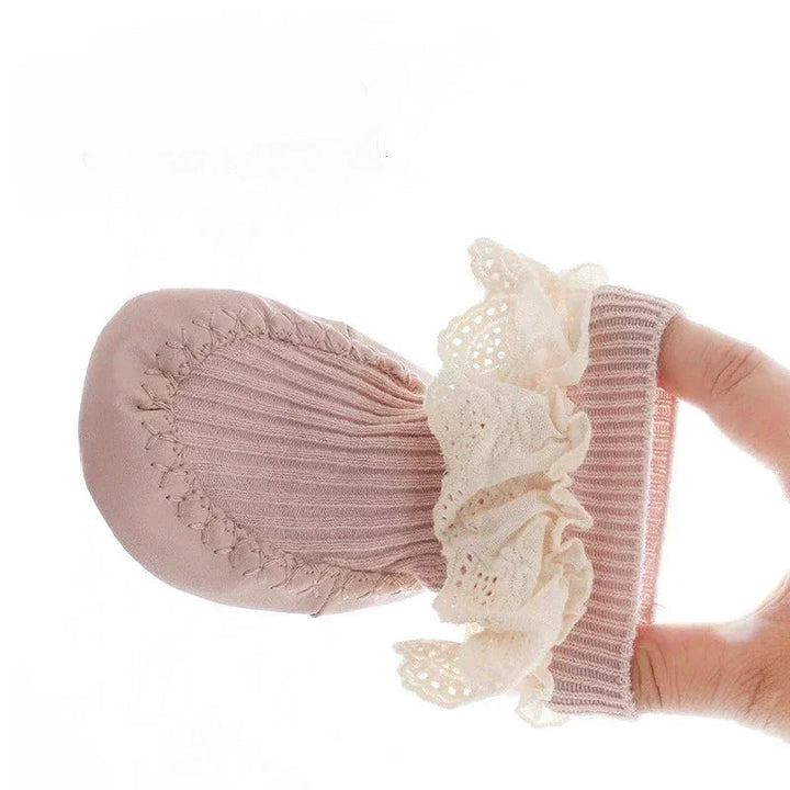 Baby sock shoe held folded to show the soft ribbed upper and cream lace cuff