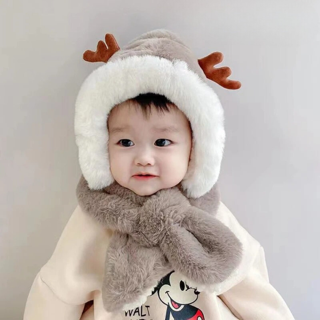 Baby wearing an antler hat with white face trim and an attached scarf around the neck