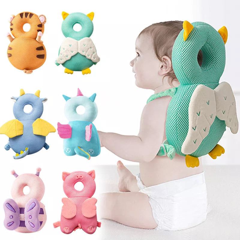 Baby wearing a green winged head cushion beside several character cushion designs