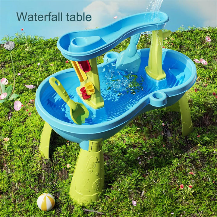 Blue water table on grass with water cascading from the upper tray into the basin