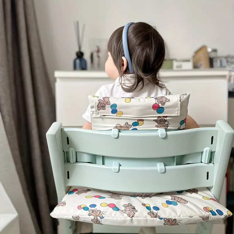 Rear view of a child using the balloon-bear cushion on a mint-green high chair