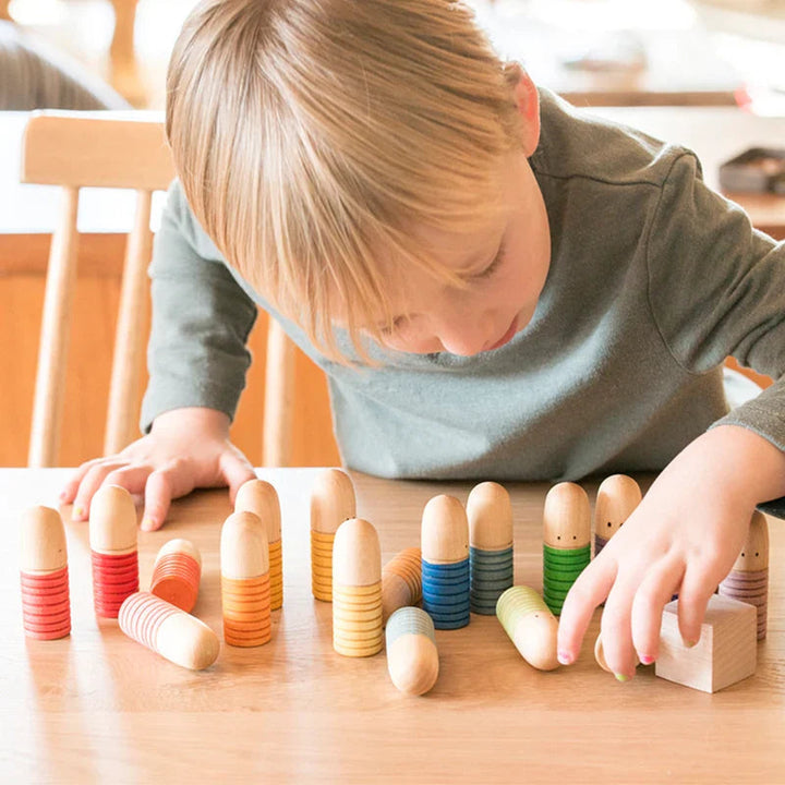 Child arranging wooden peg figures with colored bands on a tabletop