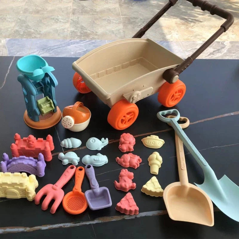 Beach wagon beside long-handled shovels, small sand tools, colorful molds and a sand wheel
