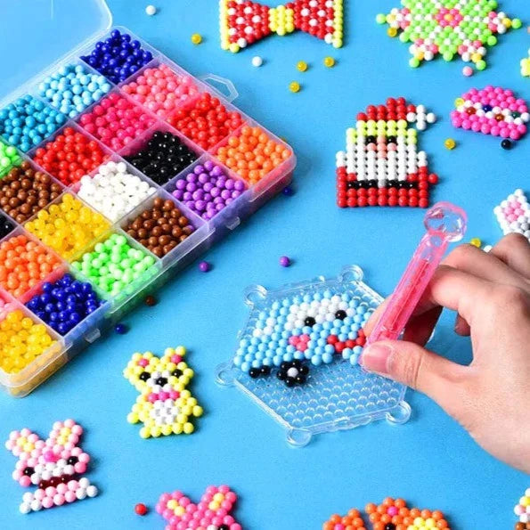 Hand using a pink bead dispenser to build a car design beside a tray of multicolored craft beads