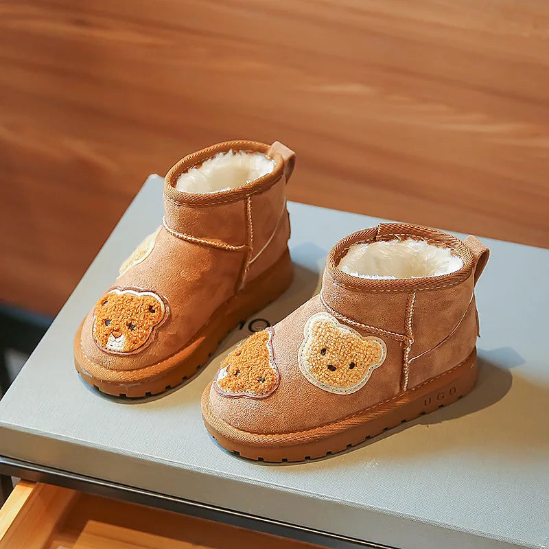 Pair of brown ankle boots on a tabletop, showing bear appliques, plush lining and rubber soles