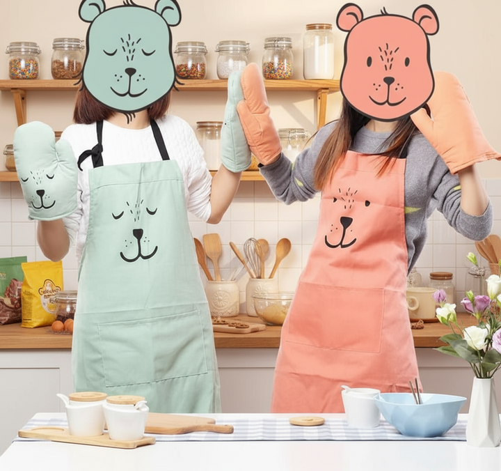 Two people wearing green and red bear aprons at a kitchen counter