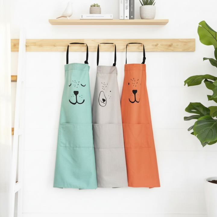 Green, gray, and red bear aprons hanging from a wooden wall rail